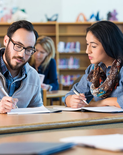 Two people sitting at a table in a library