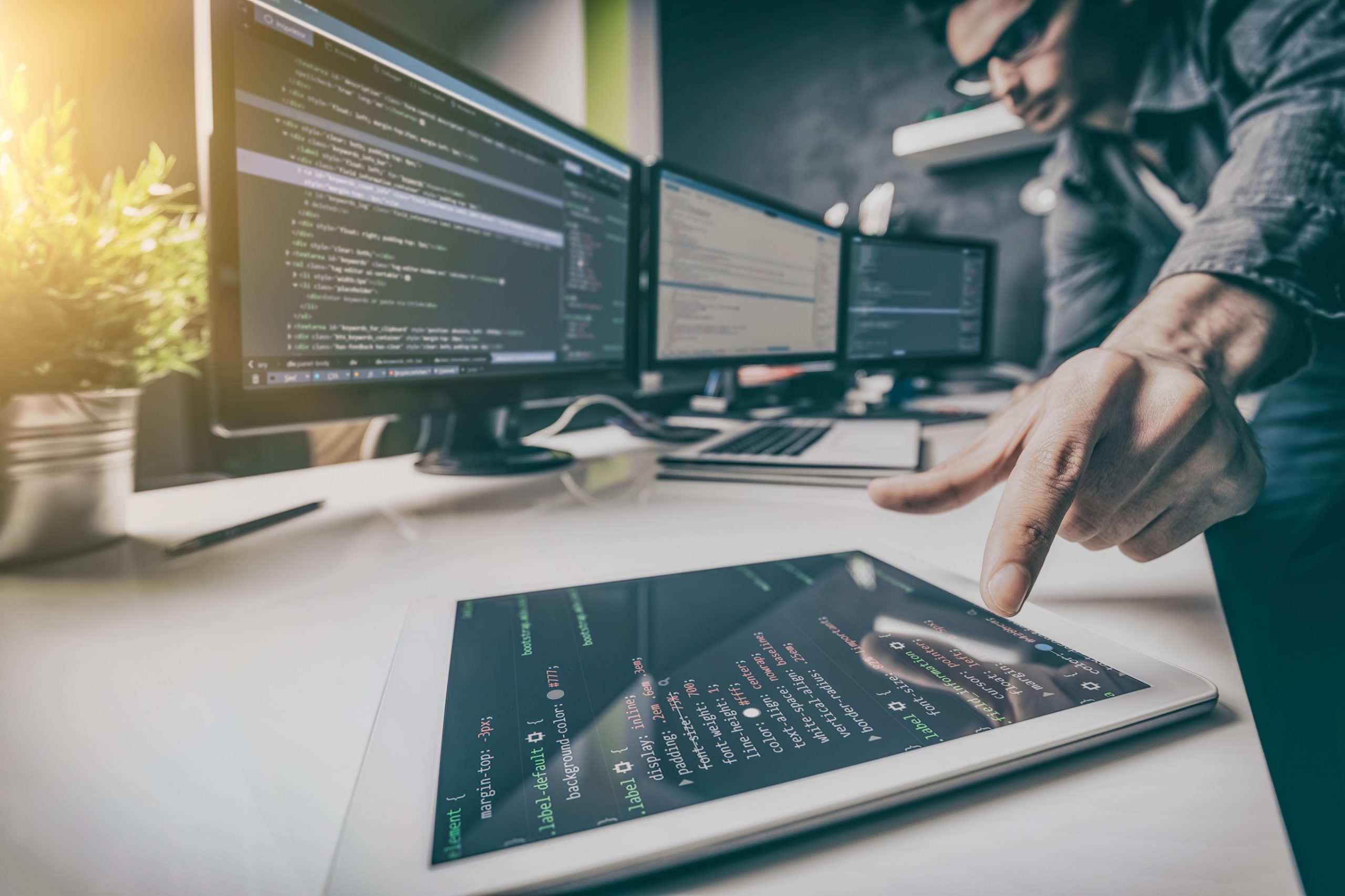 A person looking at the monitor screen and pointing his finger on the tablet screen