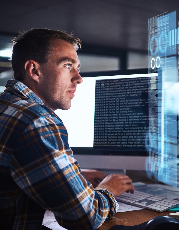 Person sitting at desk in front of a computer, staring at data