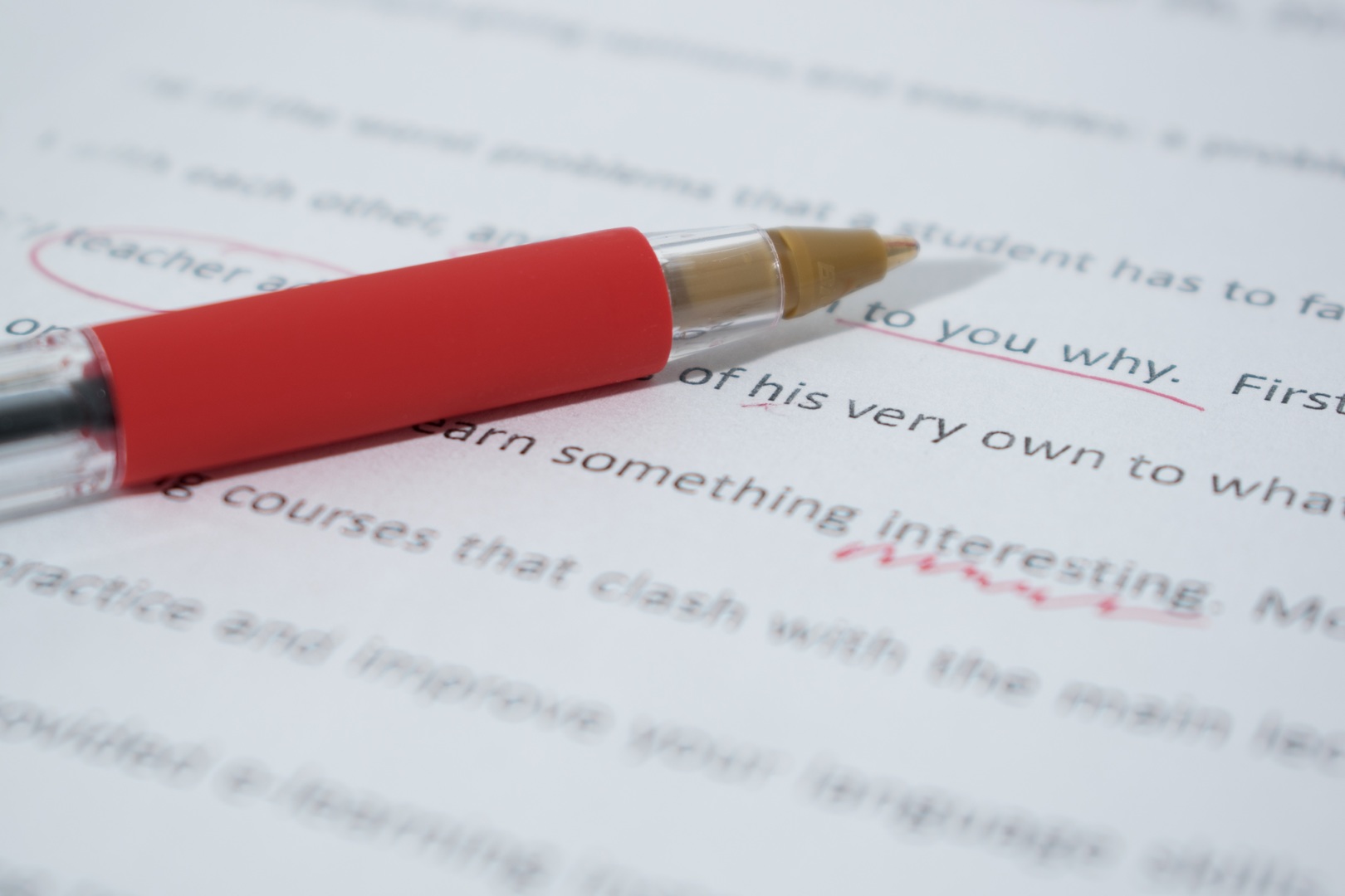 Red pen sitting atop a paper with words marked in red