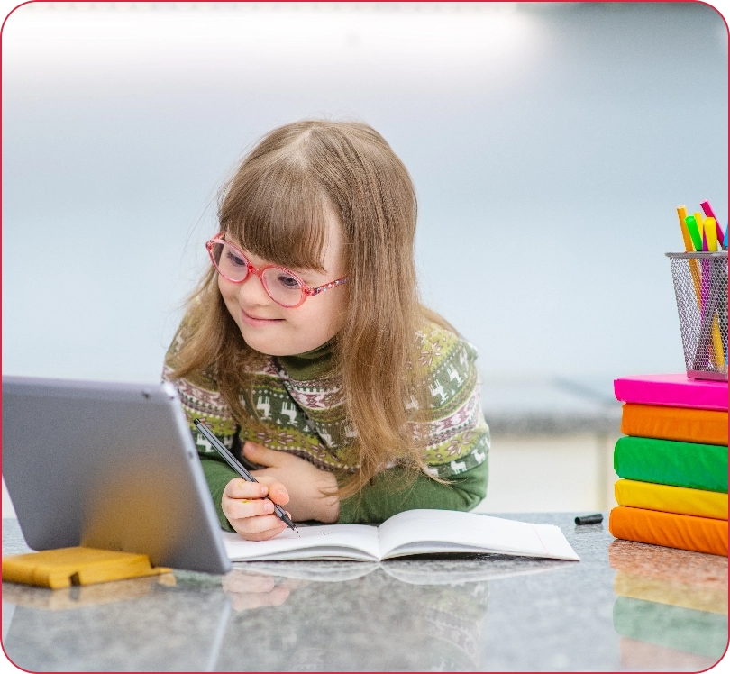 A young girl with Down syndrome engaged in lessons using a tablet